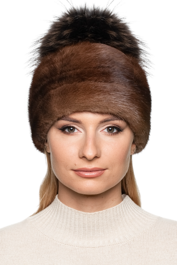 Woman wearing a brown mink fur hat with a matching brown pom pom on a white background.
