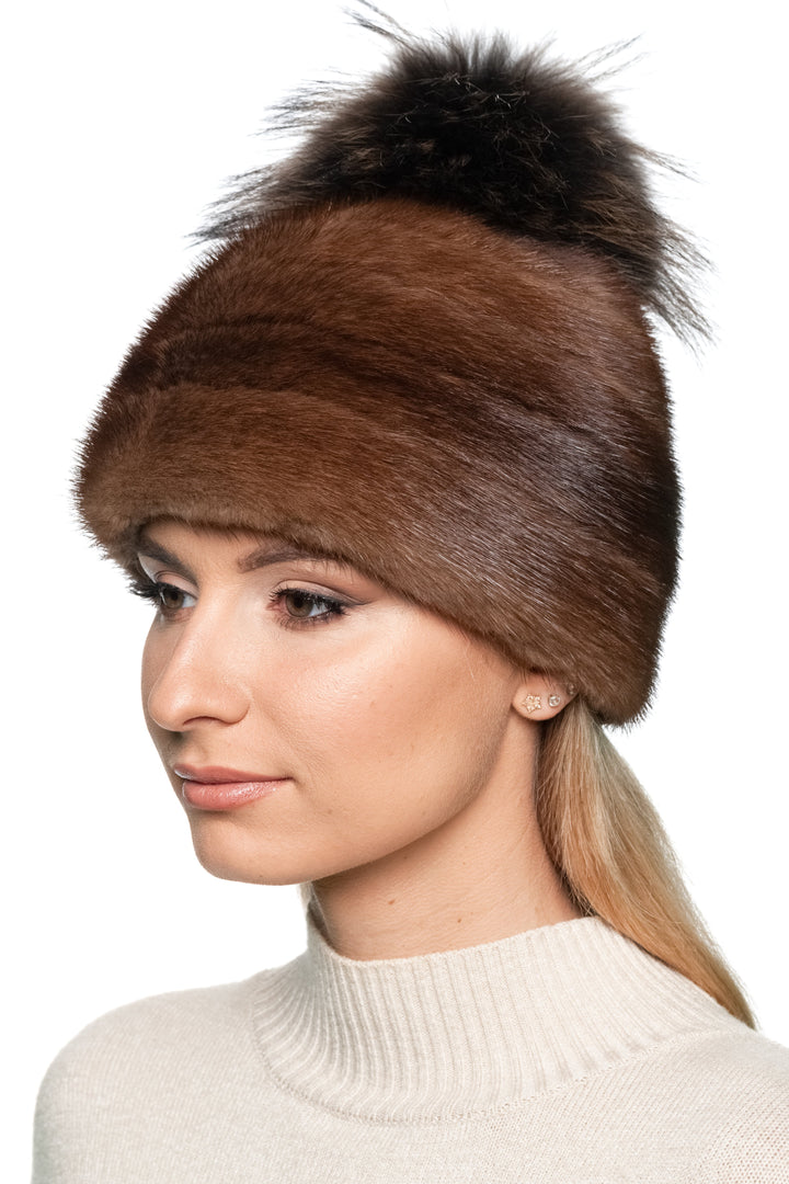 Woman wearing a brown mink fur hat with a fox fur pom-pom on a white background