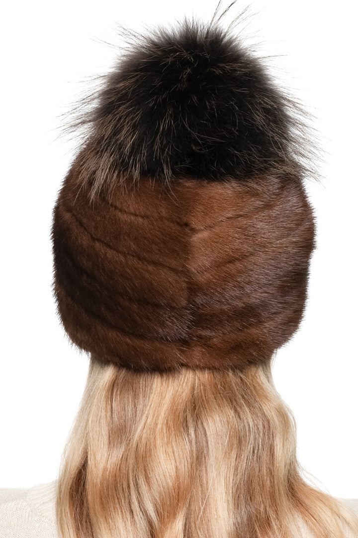Brown mink fur hat with a brown fox fur pom pom on a white background