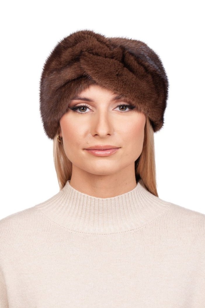 A person wearing a handcrafted accessory—a FurbySD Brown Mink Fur Headband—and a beige sweater looks directly at the camera with a neutral expression. The background is plain white.