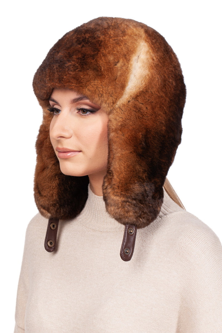 A person wearing a Brown Rex Rabbit Fur Ushanka Hat with ear flaps, a beige sweater, and a neutral facial expression.