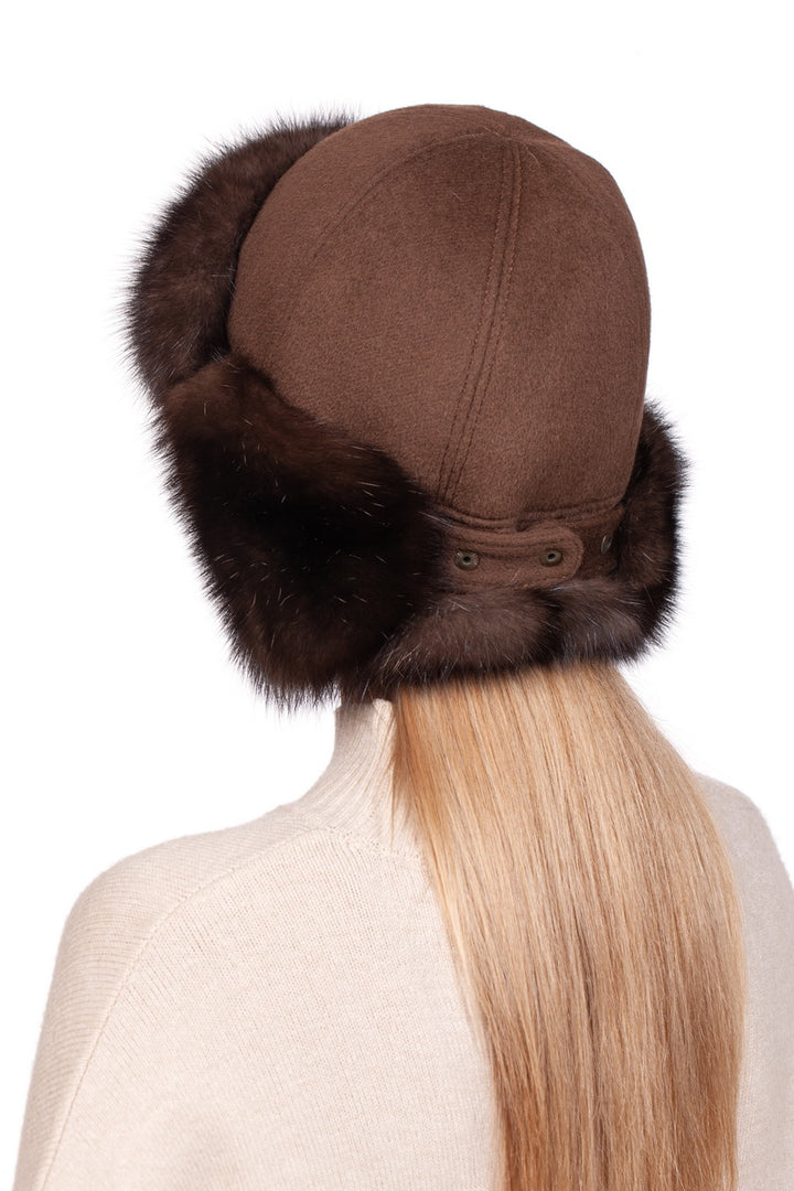 A person with long blonde hair is wearing a Brown Barguzin Sable Fur Ushanka Hat by FurbySD, paired with a beige sweater. Facing away, they highlight the back of this stylish winter accessory and their hairstyle against a plain white background.