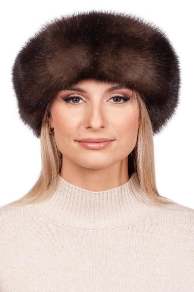 A person wearing a luxurious Brown Sable Fur Roller Hat With Cashmere by FurbySD and a beige turtleneck sweater is standing against a white background. They have long hair and are smiling slightly.