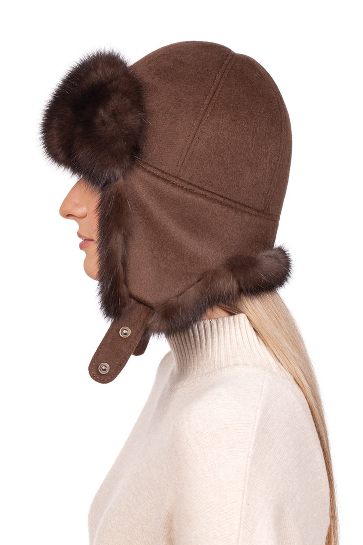 A person is wearing the Brown Barguzin Sable Fur Ushanka Hat by FurbySD, a classic winter accessory with aviator-style design and fur trim on the brim and sides. The buttons on the chin strap secure it under their long, light-colored hair against a plain white background.