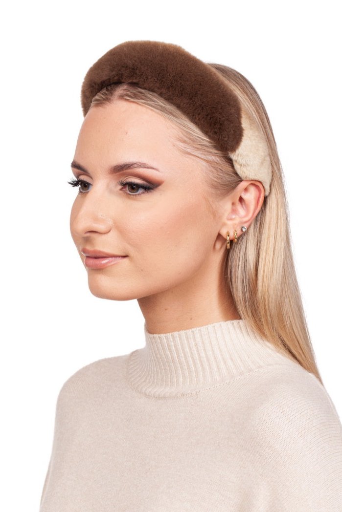 A person with long blonde hair is wearing the luxurious Brown Sheared Mink Fur Hairband by FurbySD and a beige sweater. They have gold hoop earrings and small studs, complemented by subtle makeup featuring winged eyeliner. The background is plain white.