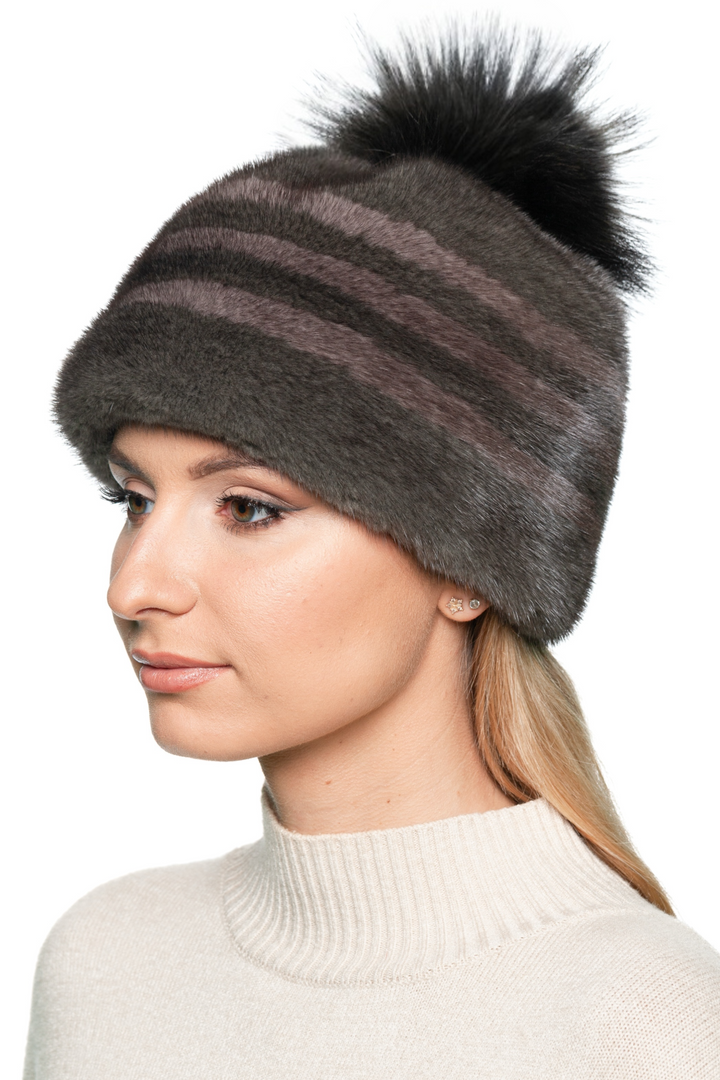 Side view of striped brown mink fur hat with fluffy fox fur bobble – elegant warm winter beanie for women.