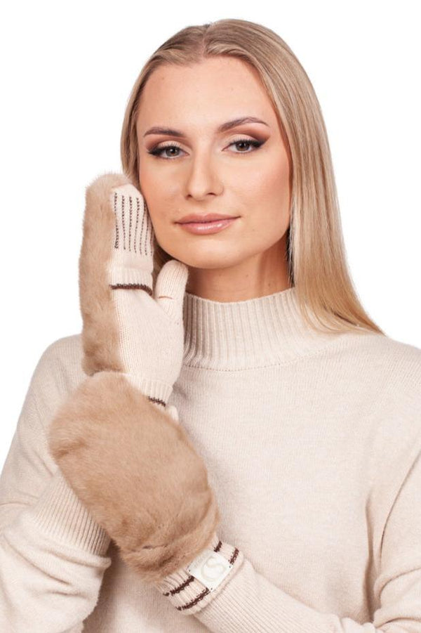 A woman with long blonde hair is wearing a beige turtleneck sweater and matching Beige Flip Top Mink Fur Mittens by FurbySD. She holds one mitten to her cheek, smiling softly against a plain white background, showcasing the perfect winter accessory.