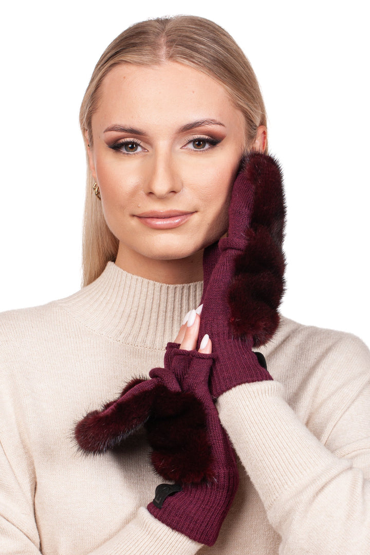 A woman with long blonde hair, wearing a beige sweater and genuine mink fur, poses elegantly with one hand on her cheek against a white background, showcasing the Burgundy Red Mink Fur Flip Top Mittens from FurbySD.