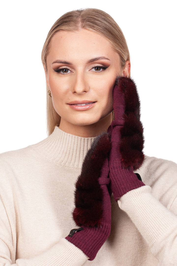 A person dressed in a light beige sweater poses with their hands, adorned in the Burgundy Red Mink Fur Flip Top Mittens by FurbySD, gently touching their face. The mittens, featuring genuine mink fur and a flip top design, stand out beautifully against the plain white background.