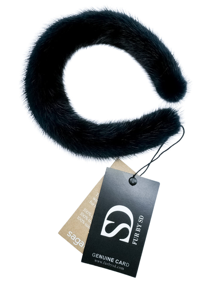 This exquisite accessory, the Dark Blue Mink Fur Hairband, elegantly spirals with its black mink fur design. It includes a tag marked "Genuine Card" and bears the "FurbySD" brand logo, which resembles an abstract 'S'. Its sophisticated style enhances any collection beautifully.