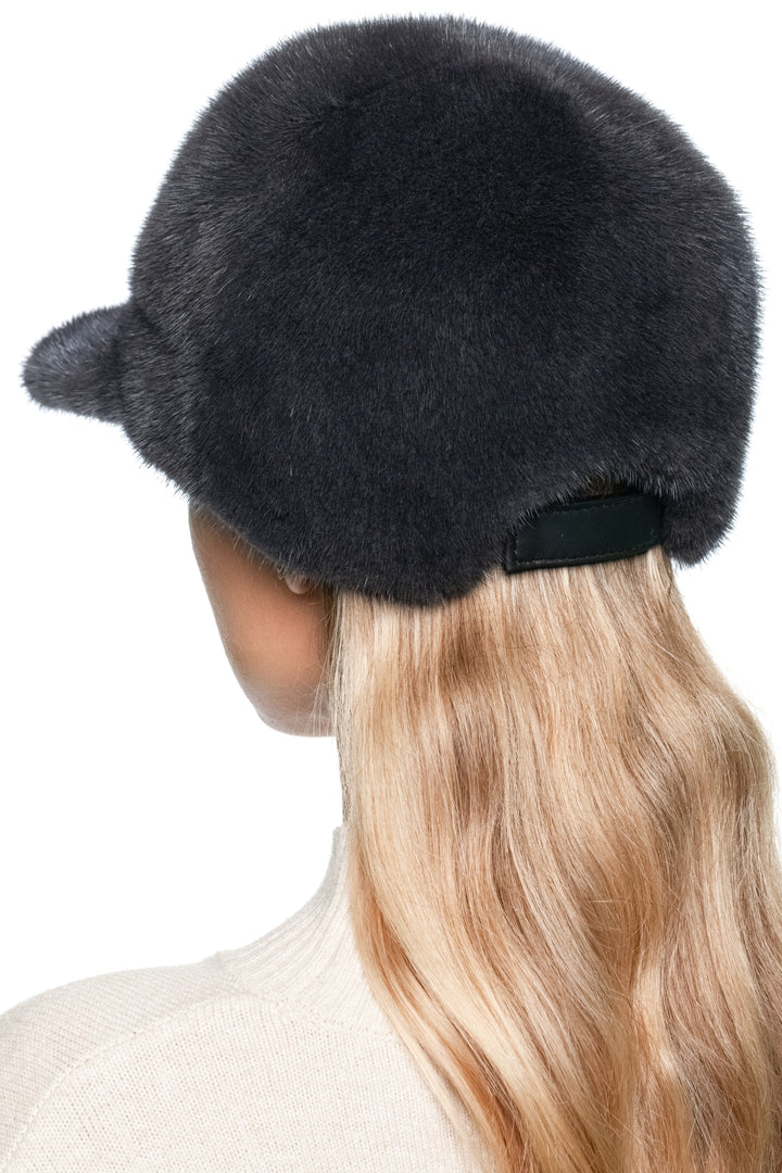 Rear angle of dark grey mink fur baseball cap on model, showing adjustable strap and rounded fur crown, handmade unisex winter hat with brim.