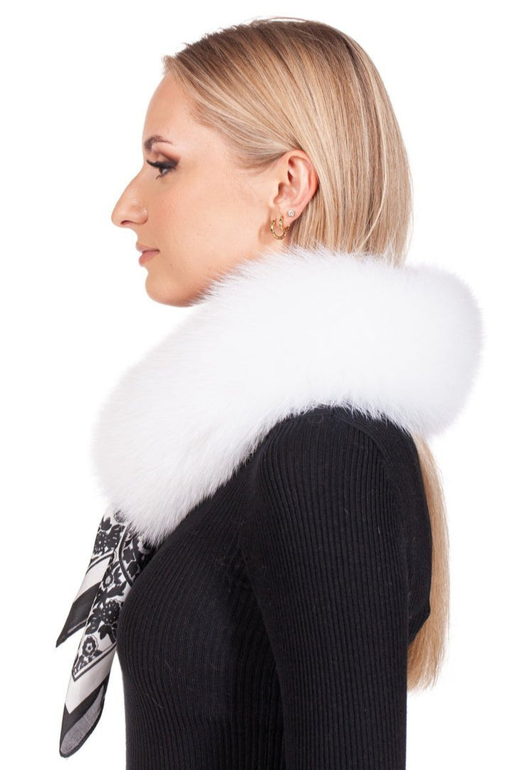 A woman with long blonde hair is wearing a black ribbed top, gold hoop earrings, and a White Fox Fur Collar by FurbySD around her neck. She gazes to the left, with an adaptable black and white patterned scarf beneath the collar.