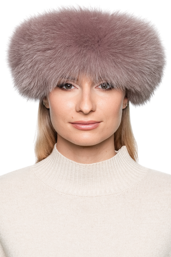 Women’s dusty pink fox fur headband, soft and voluminous real fur ear band worn across forehead, stylish luxury winter accessory.