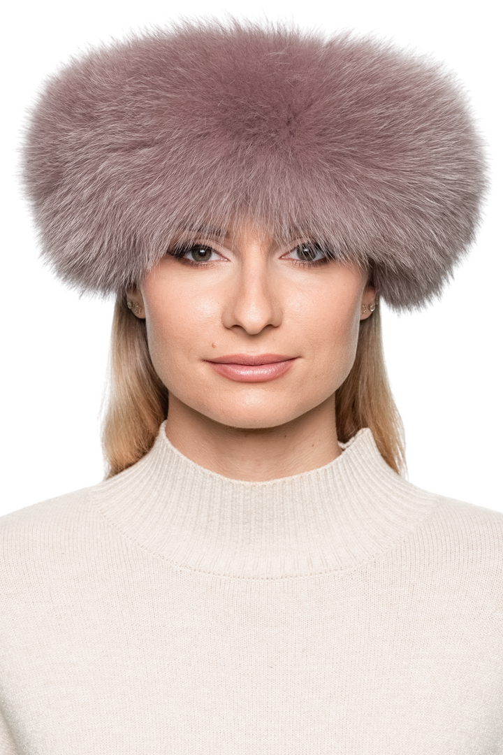 Women’s dusty pink fox fur headband, soft and voluminous real fur ear band worn across forehead, stylish luxury winter accessory.