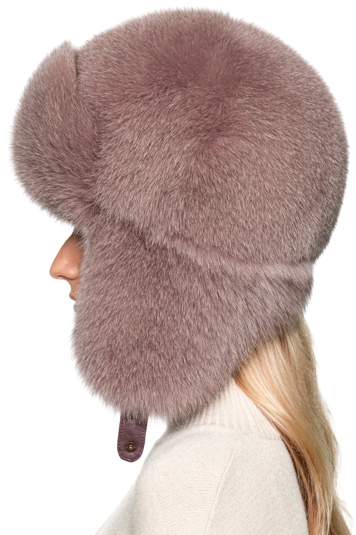 Profile view of women’s dusty pink fox fur trapper hat, thick plush fur with earflaps down, oversized ushanka style winter hat for après-ski elegance.