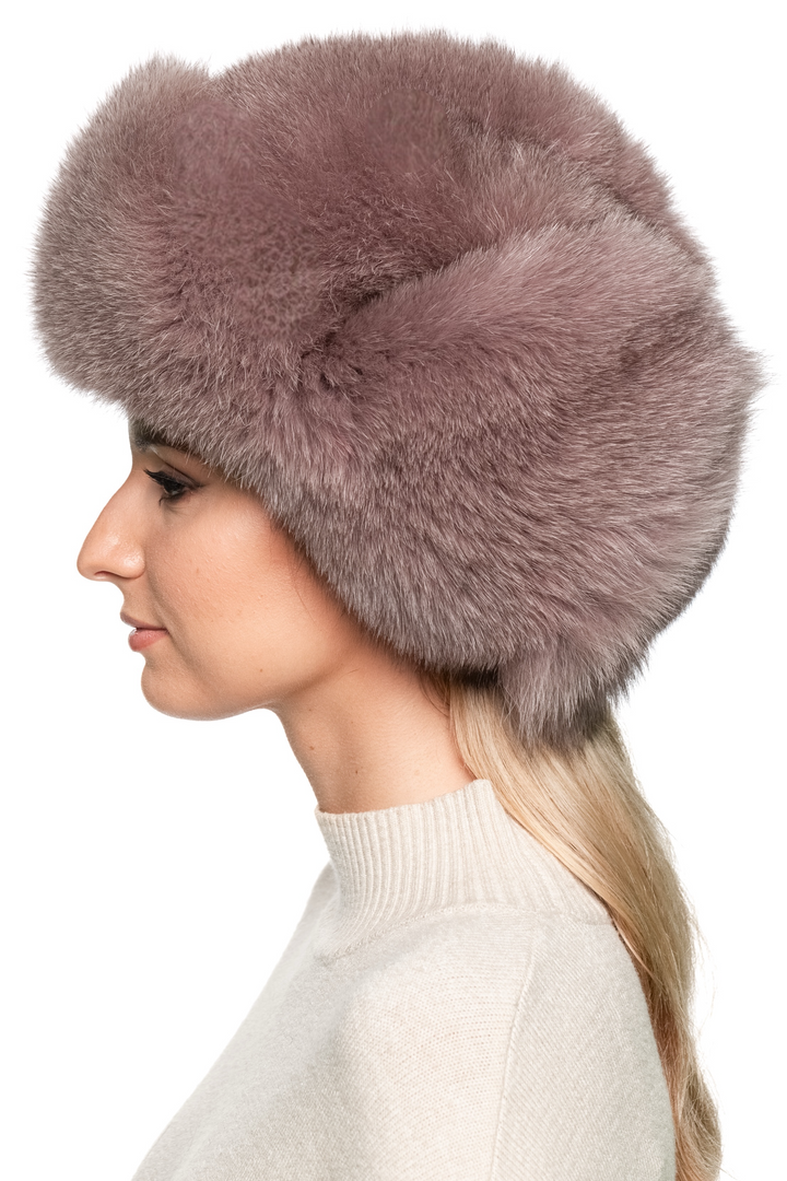 Left side profile of handmade dusty pink fox fur trapper hat for women, Russian ushanka design with oversized crown and fluffy earflaps.