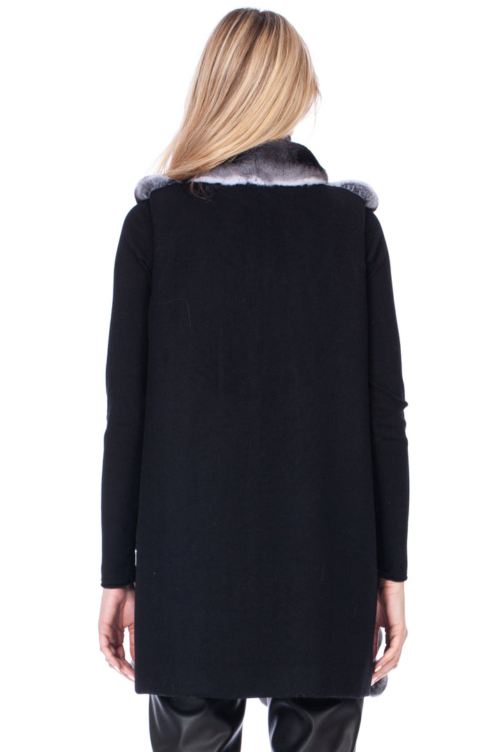 Person wearing a black cashmere coat with chinchilla fur trim on a white background.