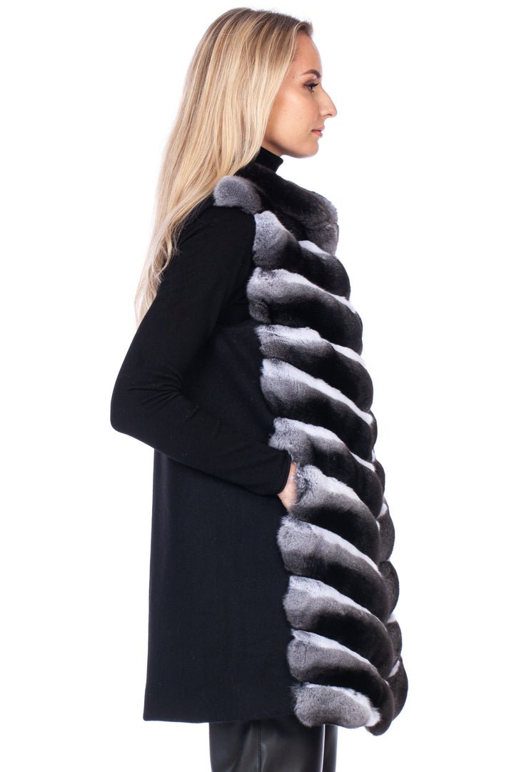 Woman wearing a black cashmere wool vest with luxurious genuine chinchilla fur trim on a white background.