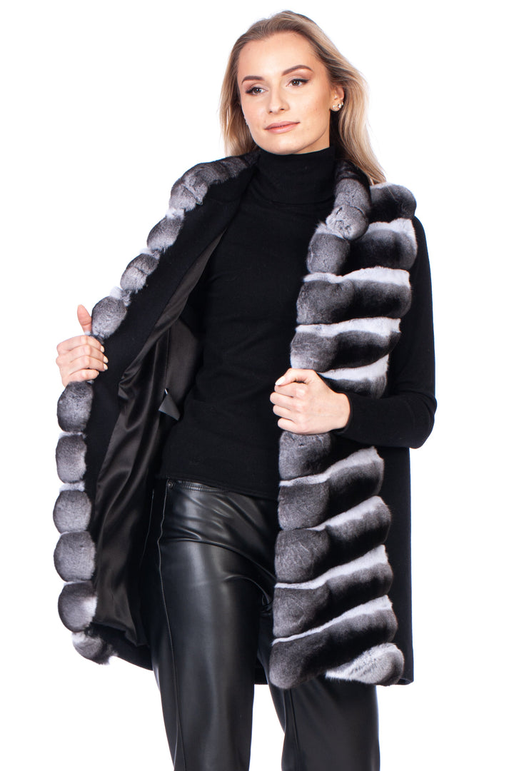 Woman wearing a black silk lined vest with genuine chinchilla fur trim and cashmere wool on the back on a white background.