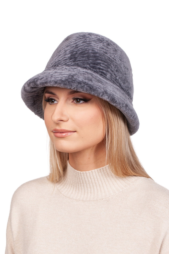 A person wearing a FurbySD Grey Sheepskin Bucket Hat with a flexible brim and a light beige sweater against a plain white background.