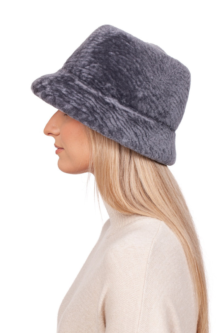 A person with long blond hair is shown in profile wearing the Grey Sheepskin Bucket Hat by FurbySD, paired with a light-colored sweater against a plain white background.