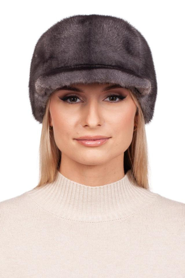 A young woman with long blonde hair wears an adjustable fit, handmade Grey Mink Fur Baseball Cap by FurbySD and a light beige sweater. She smiles slightly and looks directly at the camera against a plain white background.