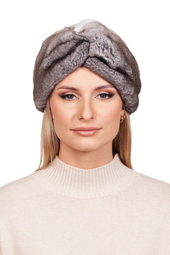 A person with long hair wears a beige sweater and the Grey Rex Rabbit Fur Headband by FurbySD, ideal as a winter accessory. This elegant headband enhances their look with light makeup and a neutral expression, all set against a plain white background.