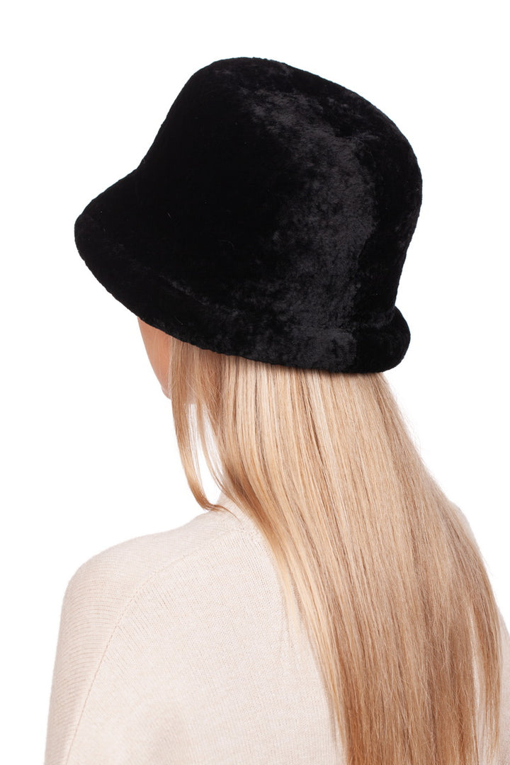 A person with long, blonde hair is seen from the back, donning a black sheepskin hat with a brim by FurbySD and a light beige sweater against a plain white background. The Black Sheepskin Hat With a Brim adds a touch of cozy elegance, making it the perfect winter accessory.