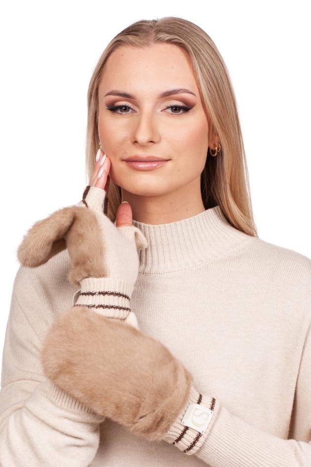 A person with long blonde hair models the Beige Mink Fur Hat and Flip Top Mittens Set by FurbySD, smiling at the camera while highlighting the soft, fluffy texture of the mittens. They wear a beige turtleneck sweater under the luxurious mink fur hat and display the flip-top mittens adorned with brown stripes.