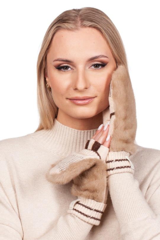 A woman with long blonde hair, wearing a beige sweater, smiles softly while holding a FurbySD Beige Flip Top Mink Fur Mitten to her face against a white background.