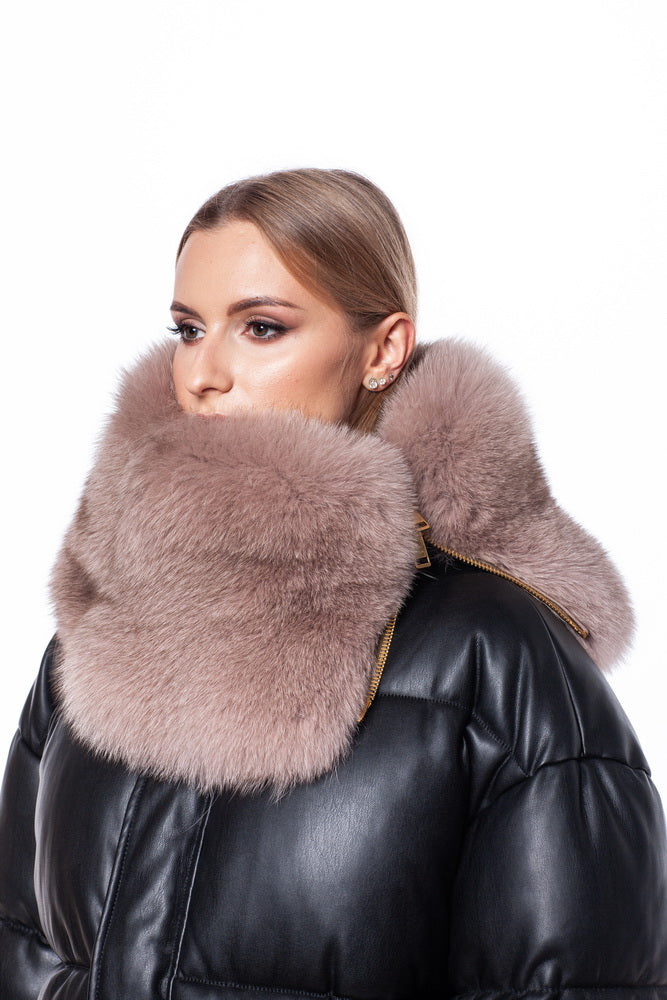 A person wearing a black leather puffer jacket with a high, fluffy Fox Fur Zipped Collar Scarf by FurbySD that covers the lower half of their face. The person has light-colored hair pulled back. This unisex winter accessory stands out against the plain white background, offering both warmth and luxury.