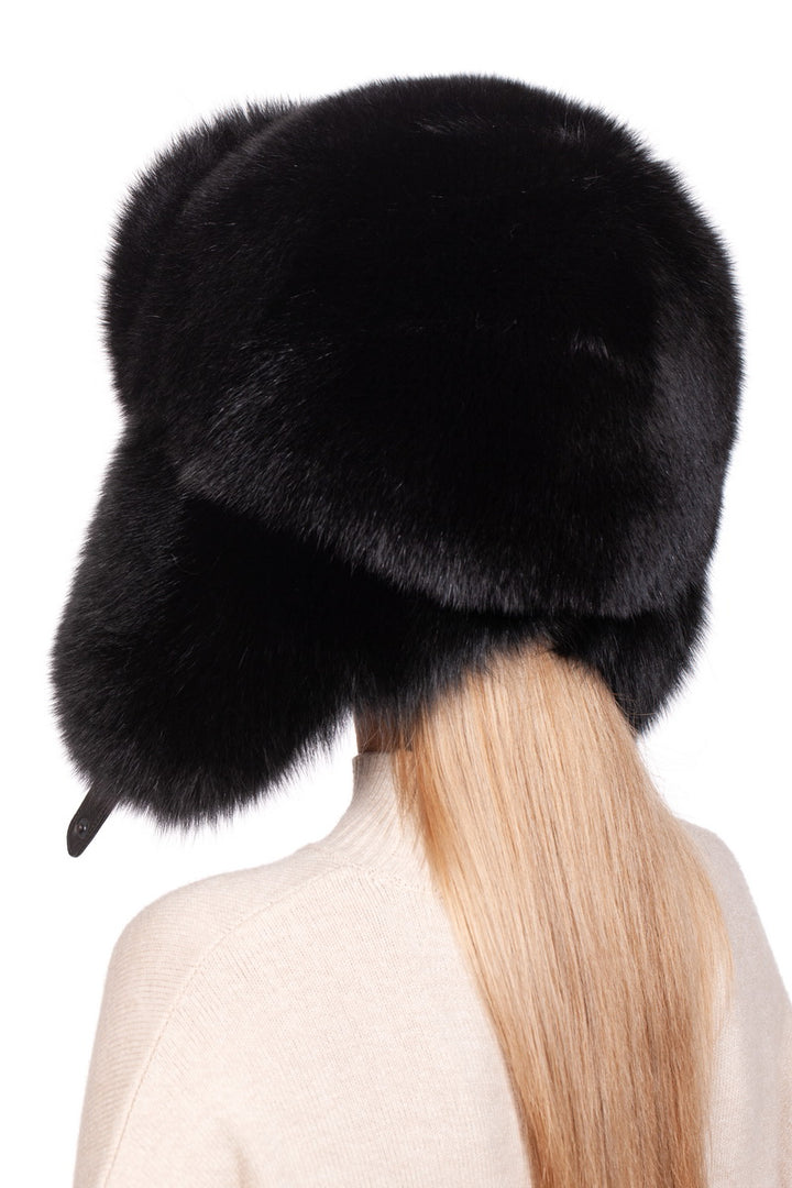 A person with long blonde hair is seen from the back, adorning a luxurious Black Fox Fur Ushanka Trapper Hat by FurbySD. This elegant winter accessory envelops most of their head. They are dressed in a light-colored sweater set against a plain white background.