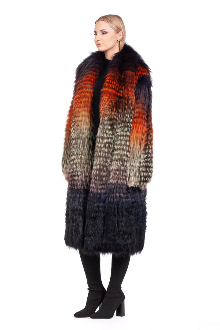 A woman is adorned in the Ultralight Fox Fur Coat by FurbySD, showcasing a luxurious blend of orange, red, brown, and black hues. Against a plain white background, she gazes to the side. Her blonde hair beautifully complements her outfit of black pants and shoes.