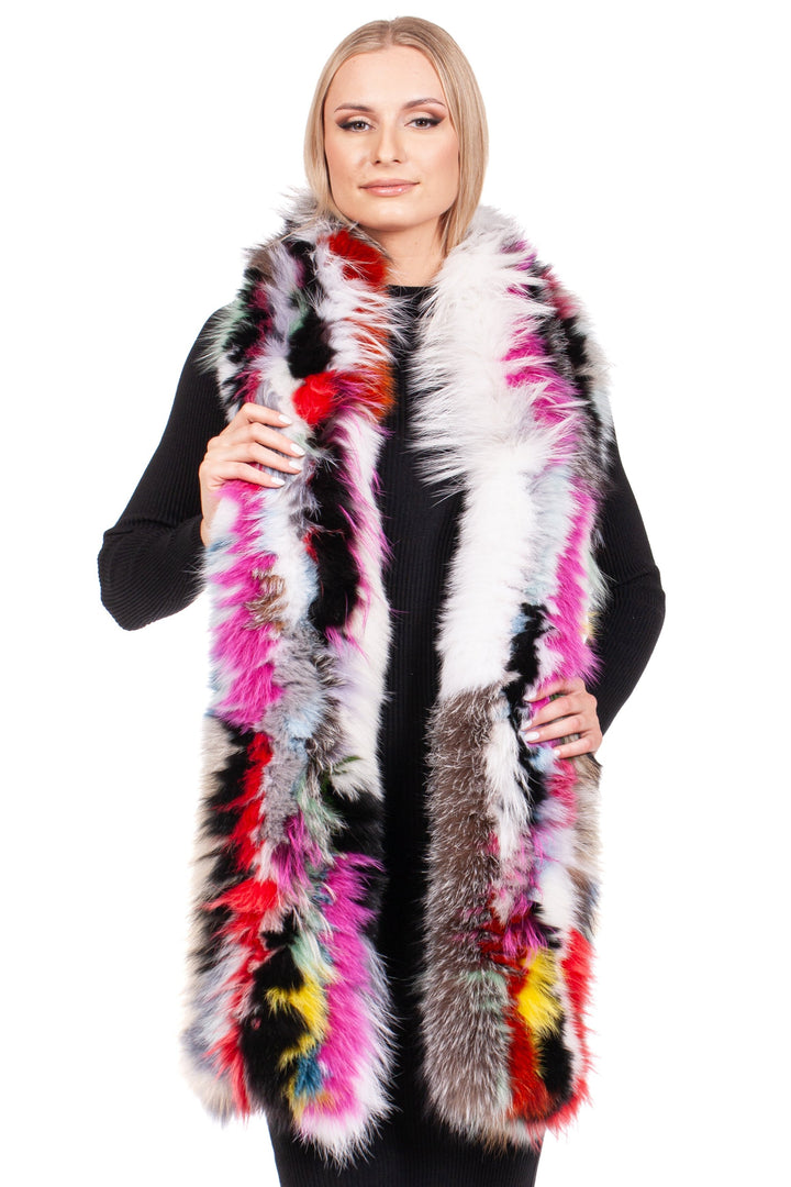 A person stands against a white background, dressed in a black outfit and showcasing a luxurious Long Knitted Fox Fur Scarf by FurbySD. This multicolor scarf features vibrant shades of pink, red, yellow, black, and white. Smiling warmly and looking directly at the camera, they exude confidence and style.