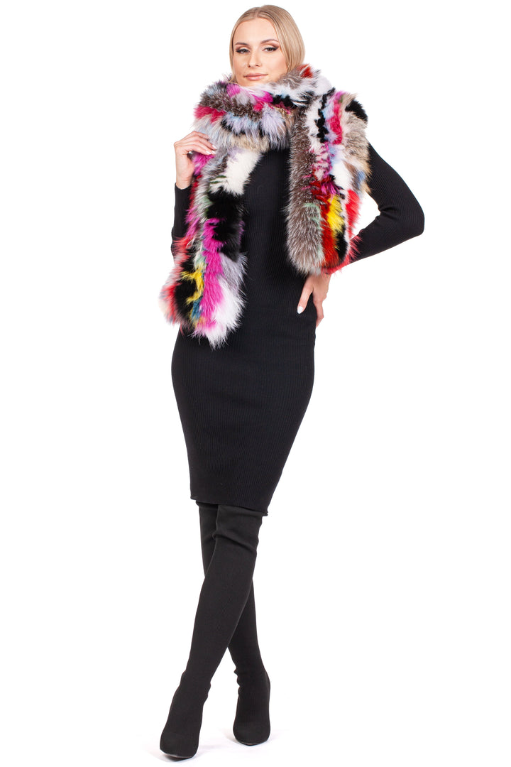 A person confidently poses in a black dress and thigh-high black boots, accessorized by the luxurious Long Knitted Fox Fur Scarf from FurbySD. This vibrant scarf features shades of pink, red, yellow, and gray and is elegantly wrapped around their neck as they stand against a plain white background, exuding style.