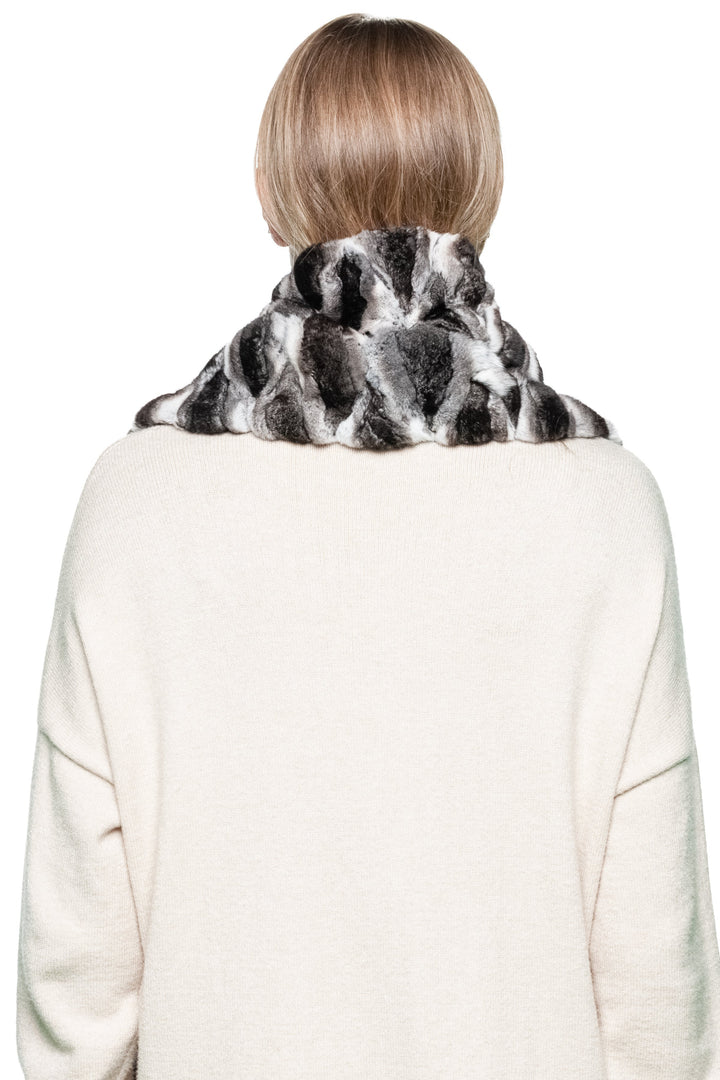 Back view of long genuine chinchilla fur scarf with natural grey-black pattern, elegant winter accessory styled over cream wool dress.