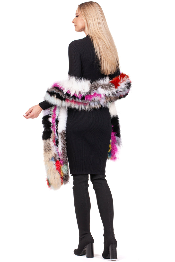 A person with long blonde hair is wearing a sleek black dress and knee-high boots. They showcase a luxurious accessory from FurbySD: the Long Knitted Fox Fur Scarf, draped over their shoulders in shades of pink, red, white, and black. They stand gracefully against a white background.