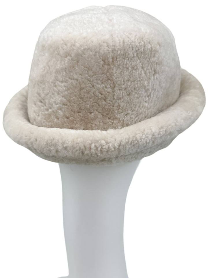 The Pearl White Astrakhan Fur Bucket Hat by FurbySD is elegantly displayed on a white mannequin head, emphasizing its soft and fluffy texture with a rolled brim.