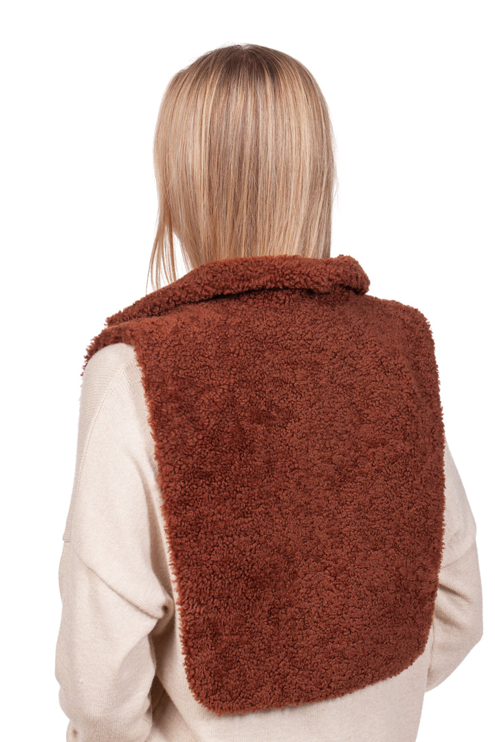 A person with long hair is wrapped in a FurbySD Brown Shearling Fur Turtleneck Collar, featuring a rich, rusty brown color draped elegantly over a cream-colored sweater. As they face away from the camera, the texture of their garment stands out against the plain white background.