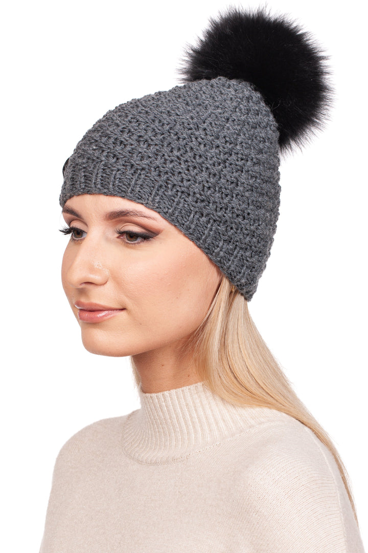 A person wearing a light beige sweater and the FurbySD Merino Beanie featuring a detachable luxurious fox bobble is facing slightly to the left against a plain white background.