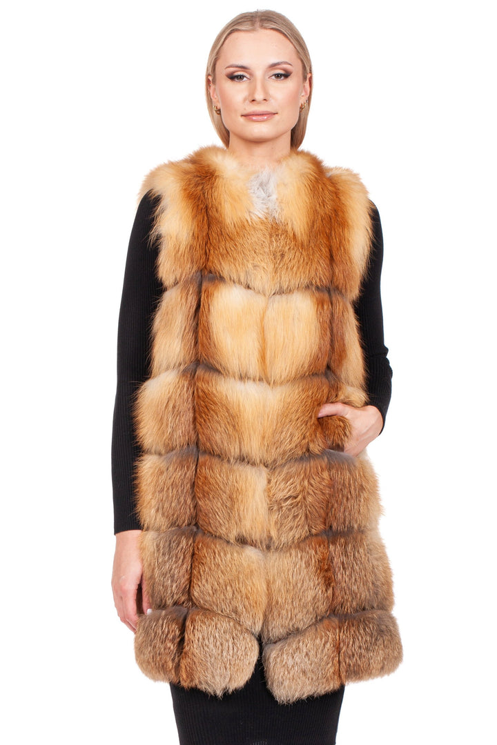 A person stands against a white background, showcasing elegance in a sophisticated winter ensemble. They wear the luxurious Long Red Fox Fur Vest by FurbySD over a black outfit and black boots, with one hand casually tucked into the vest pocket, maintaining a neutral expression.