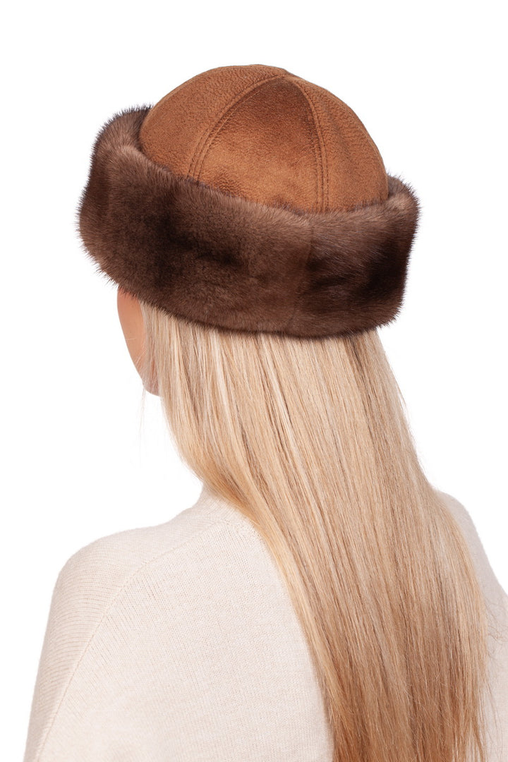 A person with long, straight blonde hair is wearing a handmade Brown Cashmere And Mink Fur Roller Hat by FurbySD. The brown suede hat, trimmed with dark brown fur, exudes elegance. The individual is seen from the back, donning a light-colored sweater against a plain white background.