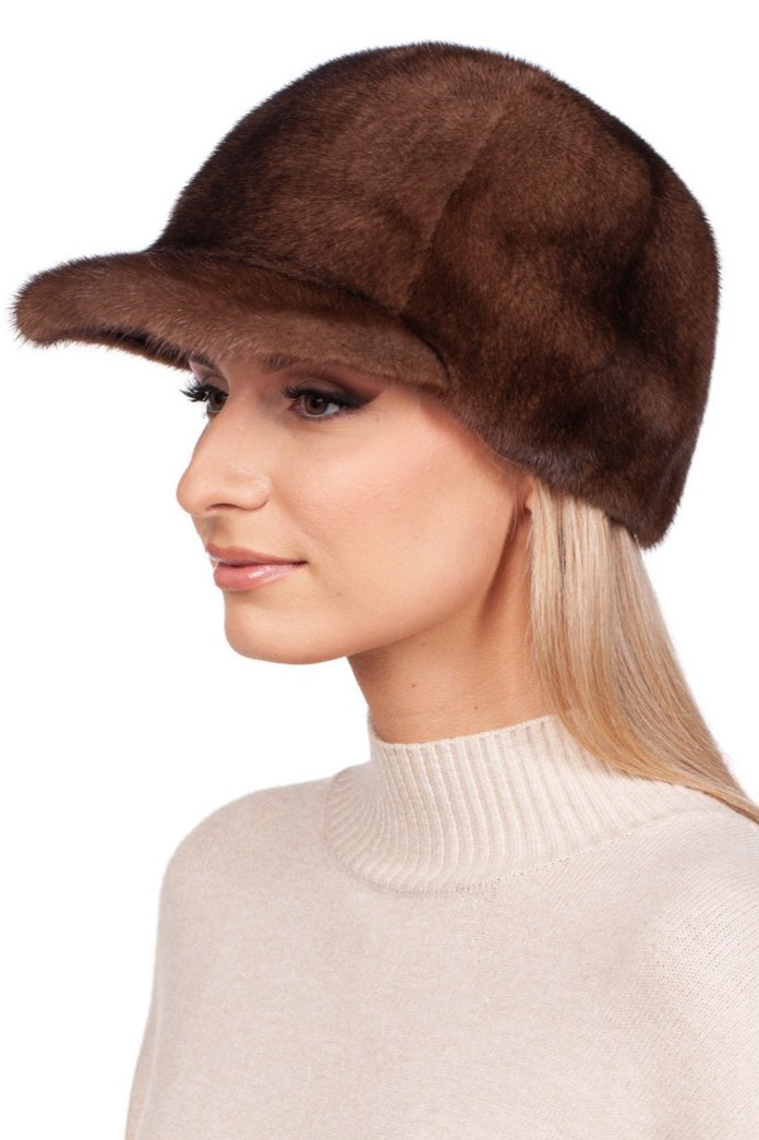 A person with long blonde hair is wearing a FurbySD Brown Mink Fur Baseball Cap with a visor. They are dressed in a cream-colored turtleneck sweater and are shown in profile against a plain white background.