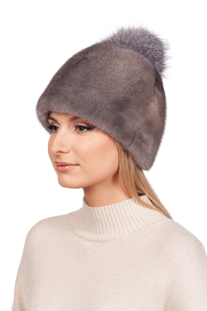 A person is wearing a cozy Mink Fur Bobble Beanie Hat by FurbySD, featuring a plush pom-pom on top, along with a light beige turtleneck sweater. The background is plain white.