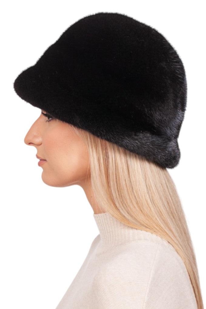 A person with long blond hair models the Black Mink Fur Bucket Hat by FurbySD, paired with a cream-colored turtleneck sweater, and is captured in profile against a plain white backdrop.