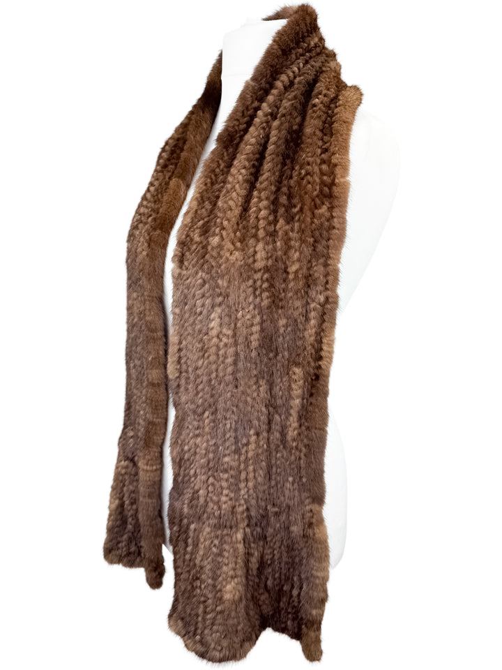 A Brown Knitted Mink Fur Scarf by FurbySD, known for its ethically sourced elegance, is gracefully draped over a white mannequin.