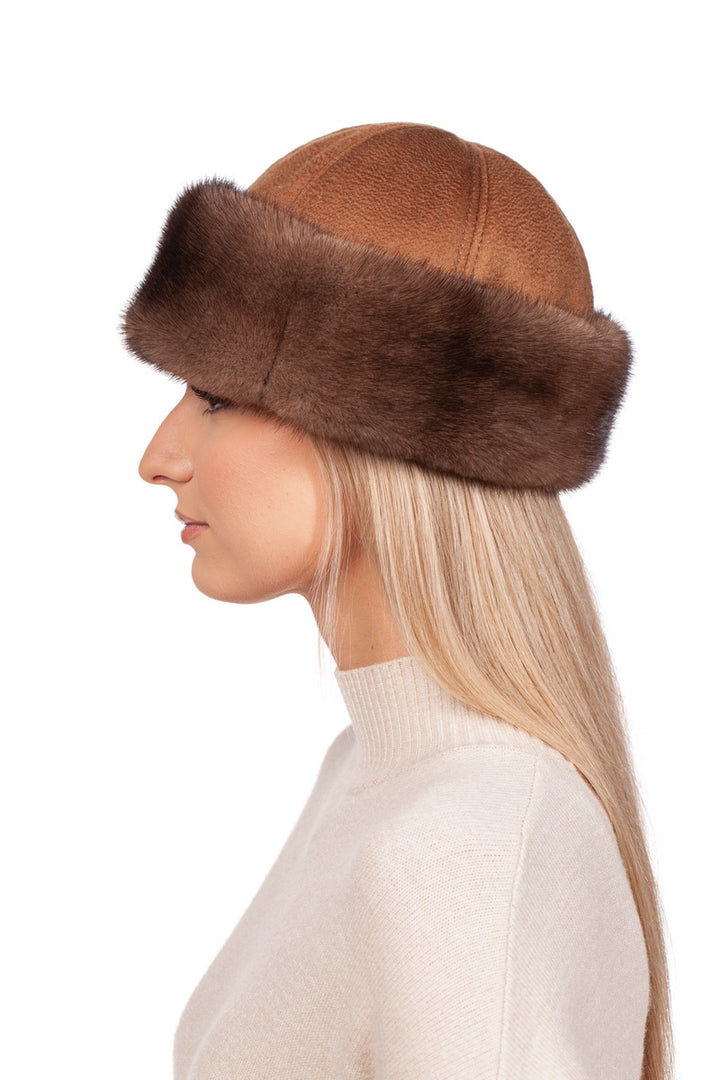 A woman with long blonde hair wears the luxurious Brown Cashmere and Mink Fur Roller Hat by FurbySD and a beige sweater. She is photographed in profile against a white background, showcasing the handcrafted elegance made in Lithuania.