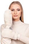 A woman with long blonde hair is wearing a beige turtleneck sweater and a pair of luxurious winter mittens from FurbySD. She elegantly poses with one Natural Pearl Mink Fur Flip Top Mitten touching her face against a plain white background.