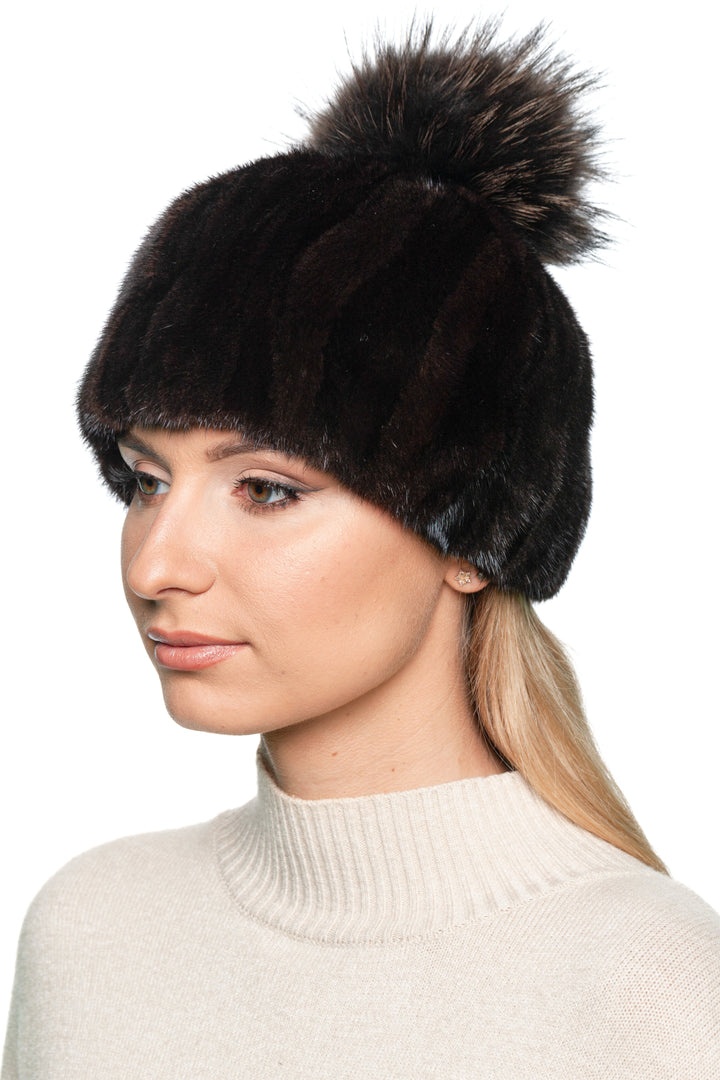 Handmade mink fur winter hat in black and brown patchwork with fluffy fox fur pom pom – stylish women’s winter accessory, side-front angle.
