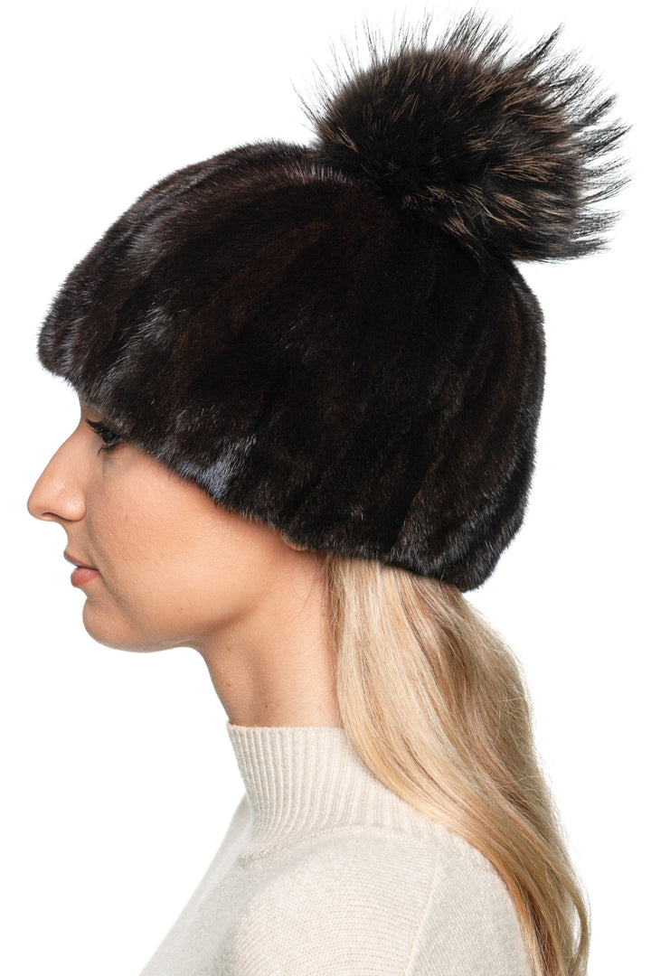 Designer mink fur hat with black and brown patchwork and fox fur pom pom – elegant women’s winter hat, side profile view.